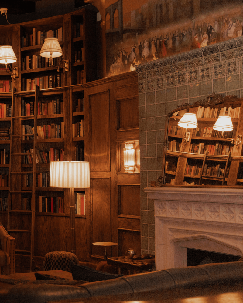In the library, Visual Comfort's light highlight the height of the shelves, while reflections in the mirror double the glow, giving the room both structure and softness.