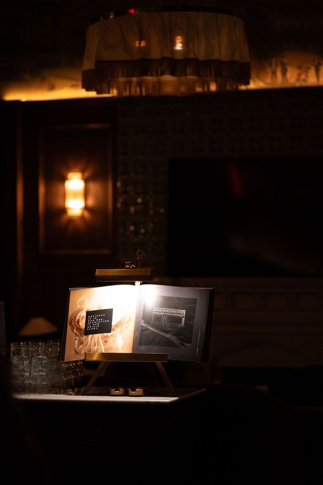 A quiet moment captured under warm light. An open book draws focus in an intimate, dimly lit Maxwell's corner