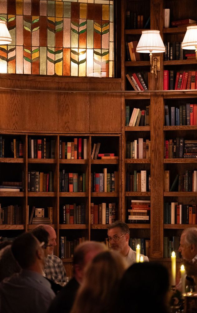 Shelves filled with books sit beneath two pleated-shade wall lights