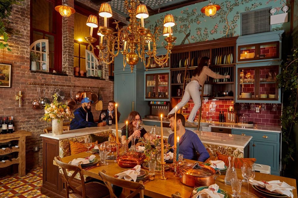Guests enjoy dinner in Maxwell's Grand Kitchen surrounded by copper Ruffoni cookware, elegant chandeliers, and hand-painted cabinetry.