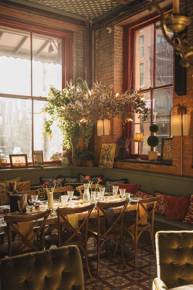 Maxwell’s Garden Room, surrounded by greenery, floral arrangements, and warm-toned decor by Cox London