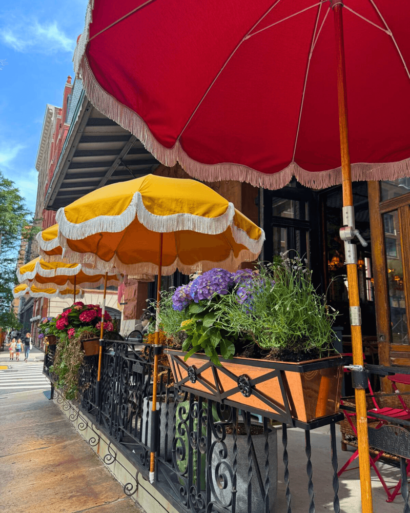 Sidewalk view of Maxwell’s patio with yellow striped umbrellas and planters.