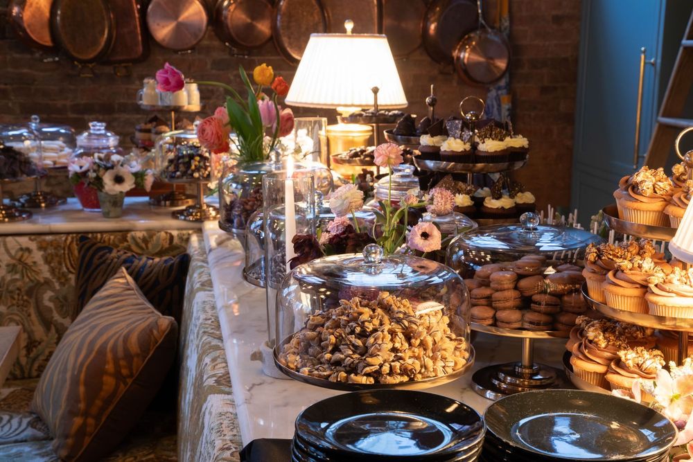A dessert table that feels like a celebration in itself, layered with glass domes, fresh flowers, and hand-finished treats