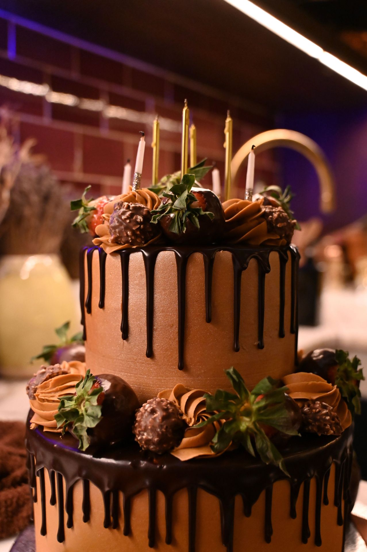 The centerpiece of the night — a chocolate cake crowned with gold-tipped candles.