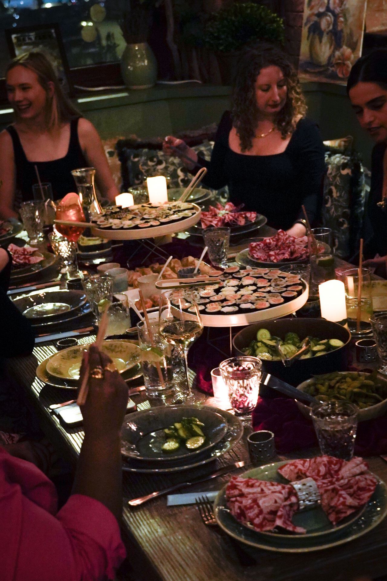 women gathering around shared tables, building community through conversation and cuisine in intimate, candlelit settings