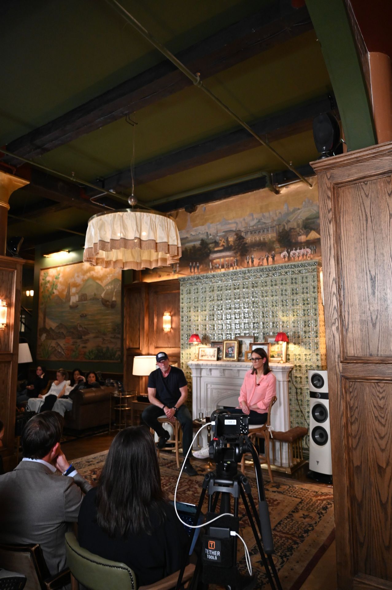 The conversation unfolds against Maxwell’s signature backdrop