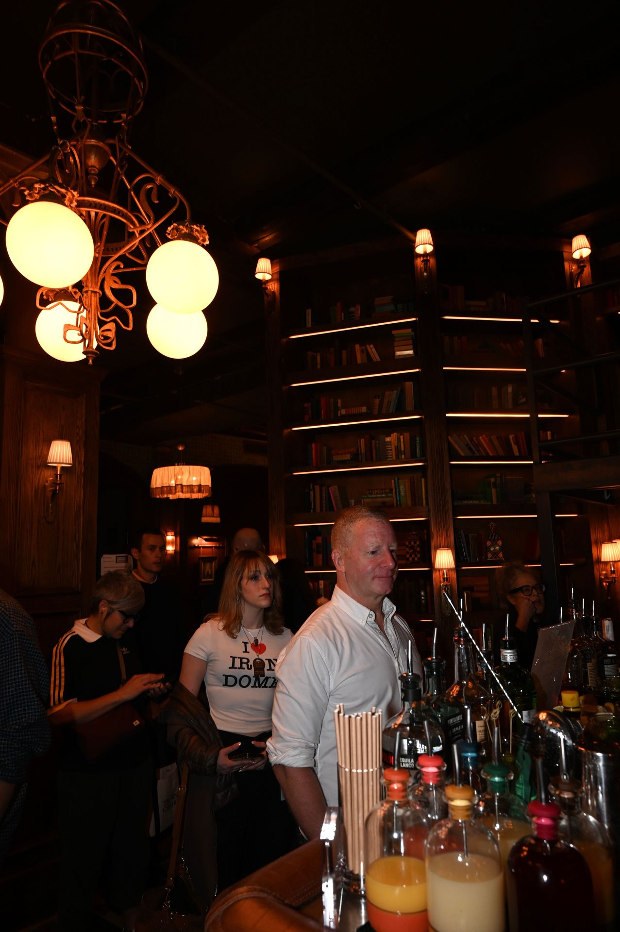 Guests gathered at the bar under the warm glow of the library shelves