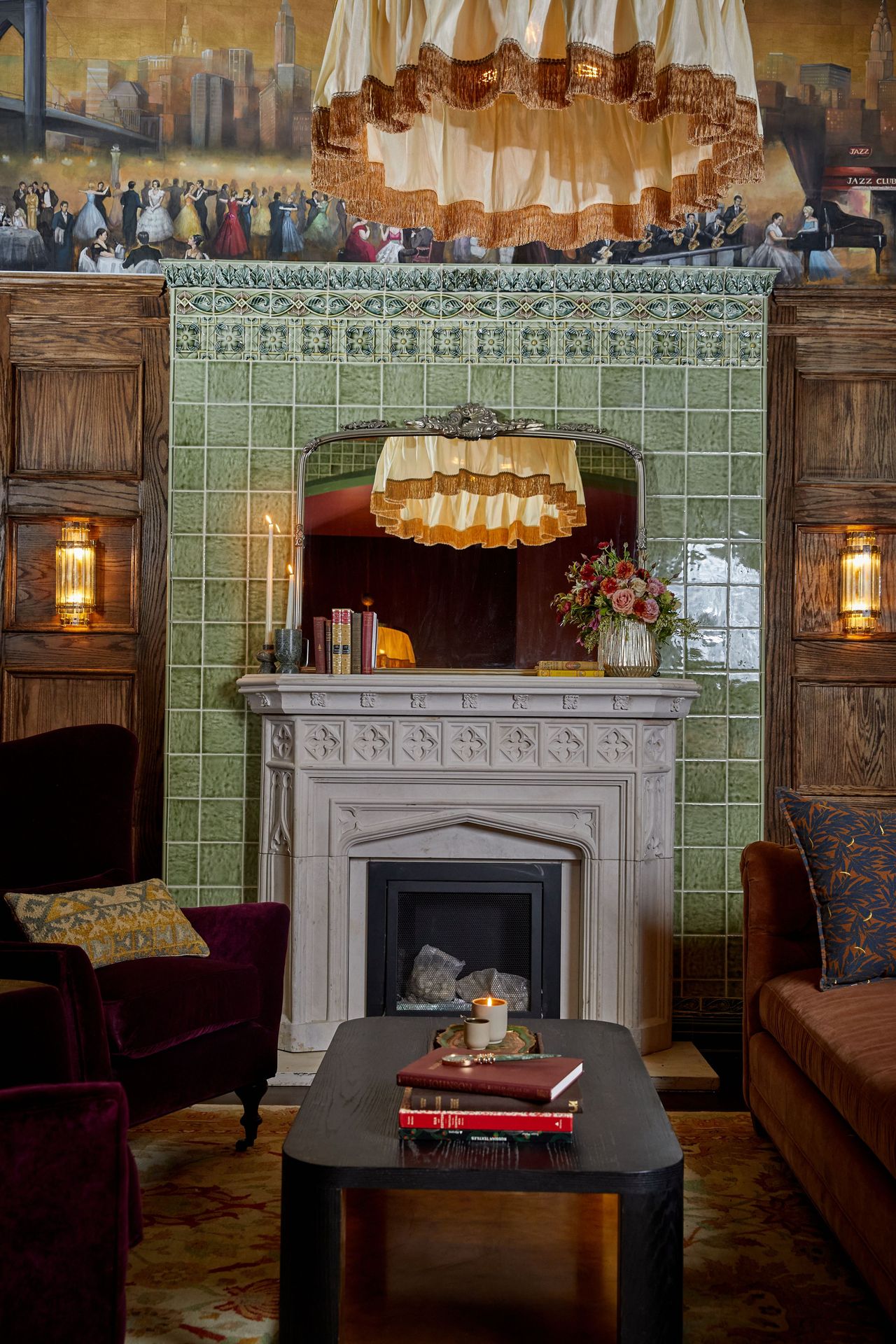 Framed by wood paneling and green tilework, the carved stone fireplace anchors the room with a quiet sense of structure