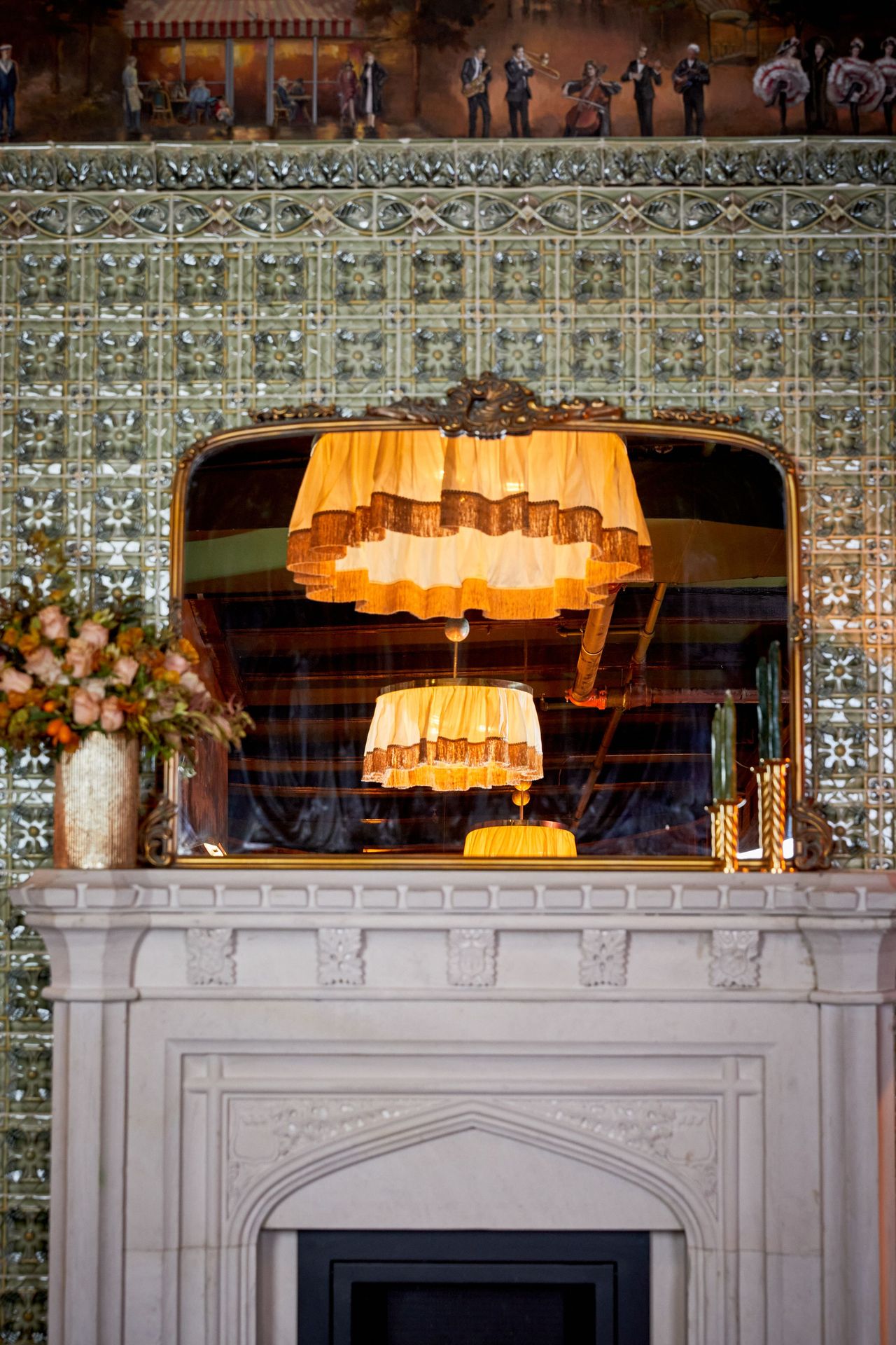 A mirror over the fireplace doubles the light of the fabric-shaded fixture above