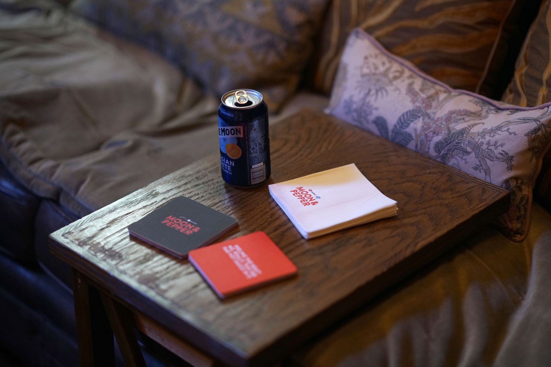 A cozy corner with Moon & Pepper details: coasters, Blue Moon Belgian White, and plenty of inviting pillows.