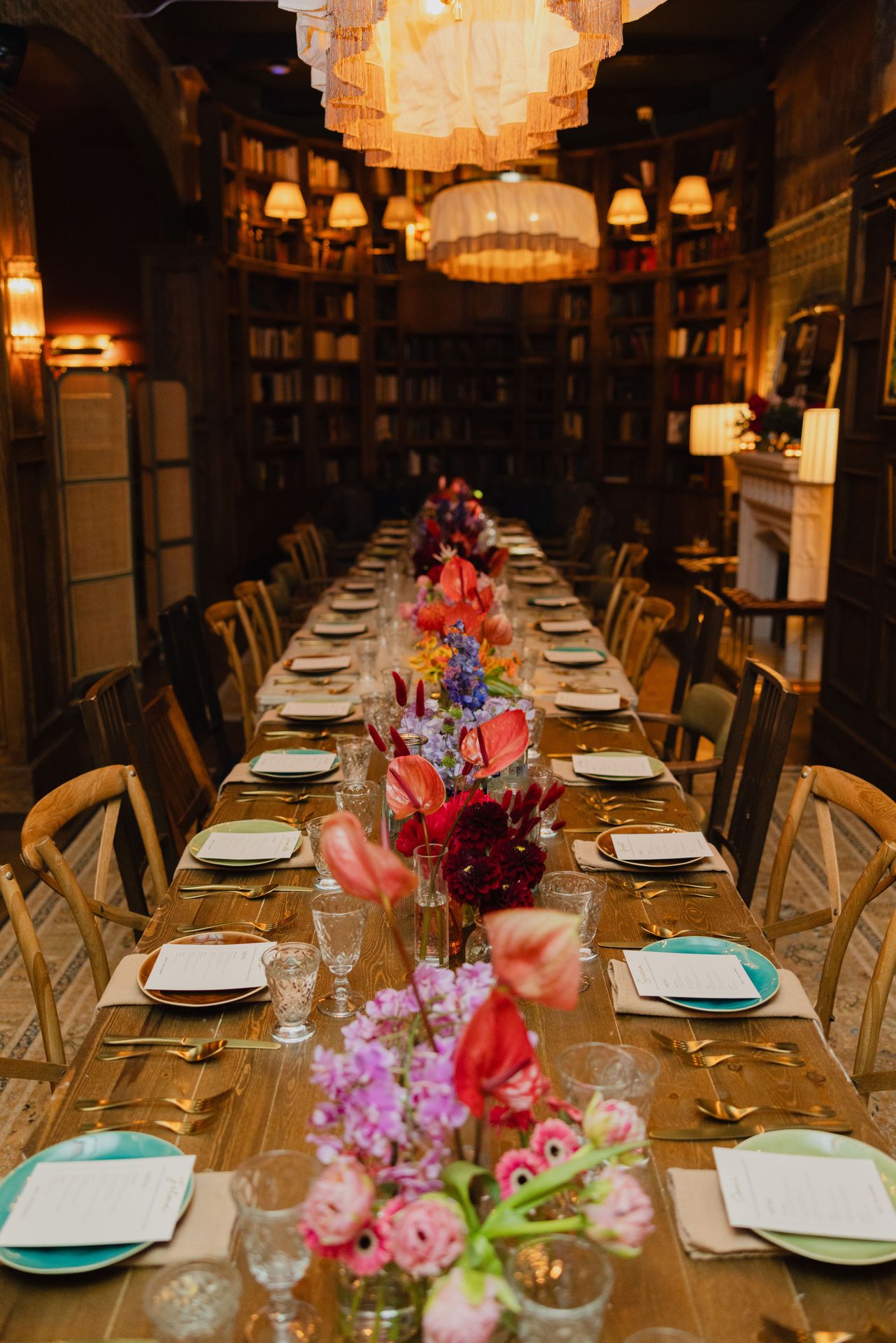 A long, elegantly set table adorned with vibrant florals awaits the evening’s guests