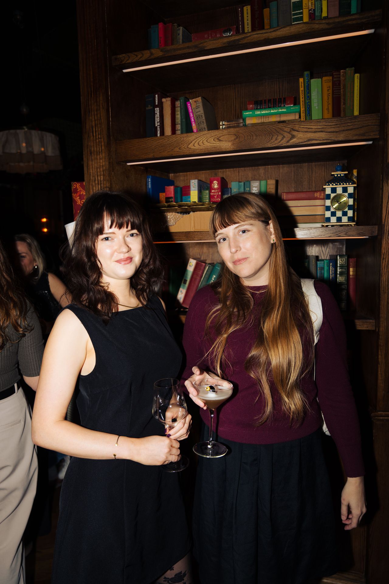 Guests mingled between the shelves with cocktails in hand